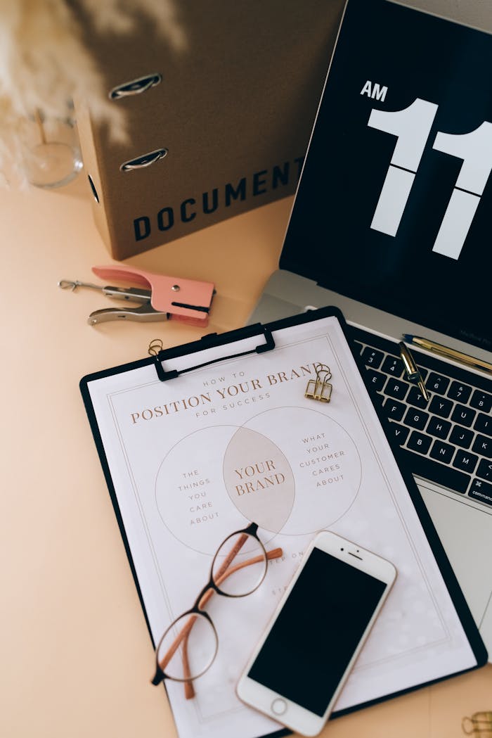 Organized workspace with documents, laptop, smartphone, and glasses