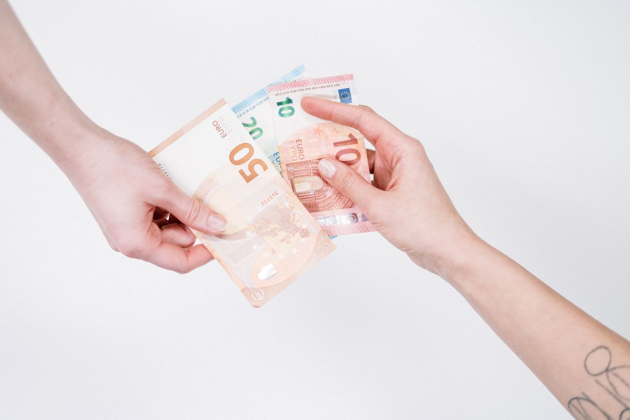 about-us Close-up of hands exchanging euro banknotes, symbolizing financial transactions and currency exchange.