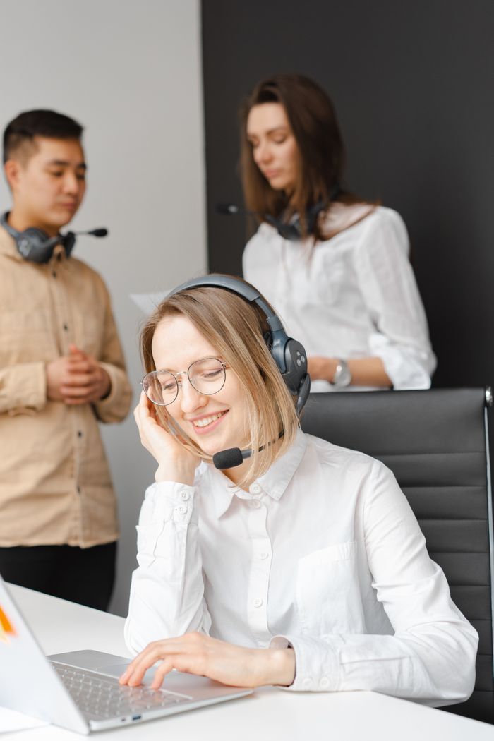 who-we-are Customer service team working together in a modern call center with headsets and laptops.